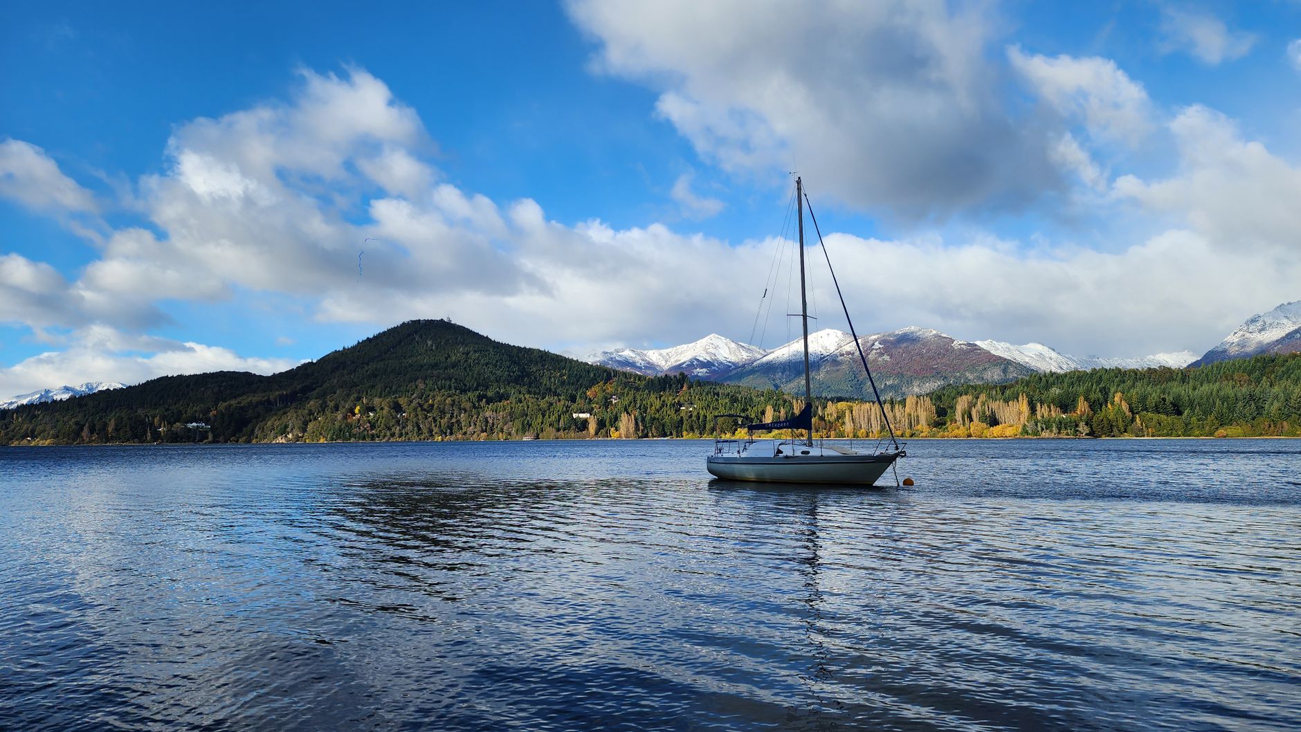 A tranquil sailboat on a lake with snowy mountains in Bariloche, Argentina.