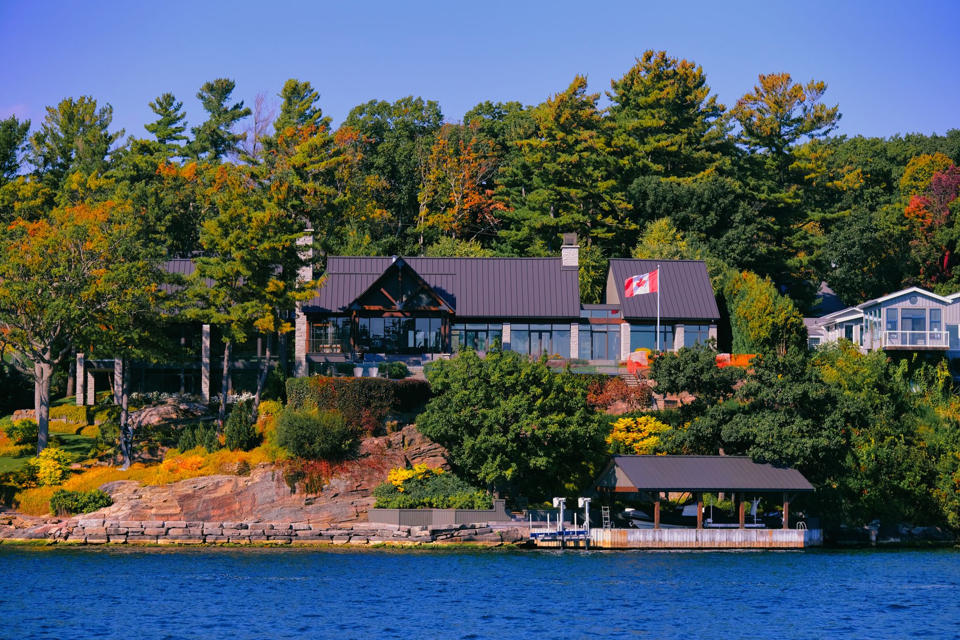 Beautiful lakefront house surrounded by colorful autumn trees in Canada.