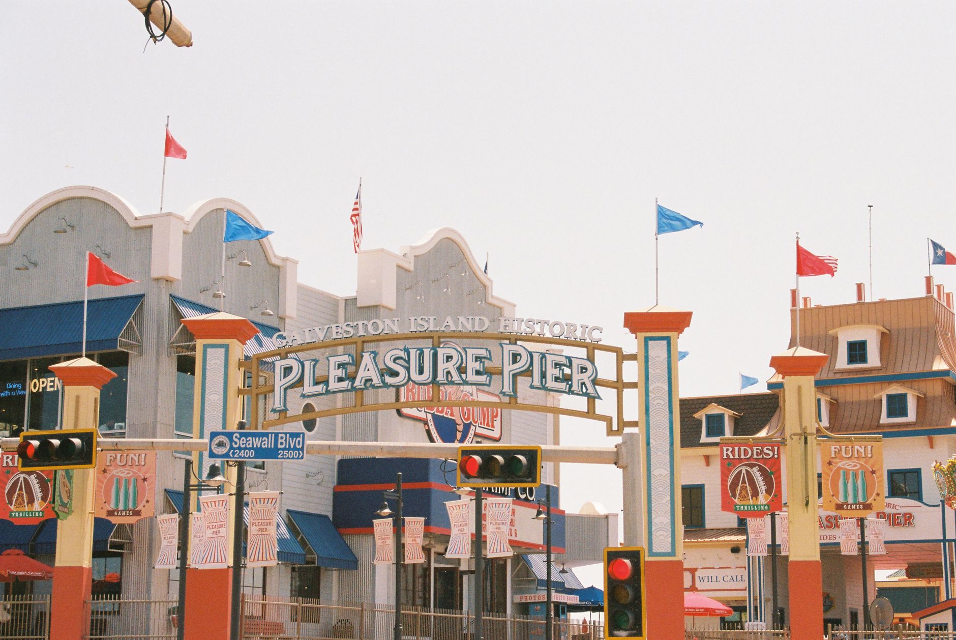 Scenic view of Galveston Island's iconic Pleasure Pier with flags and signs.