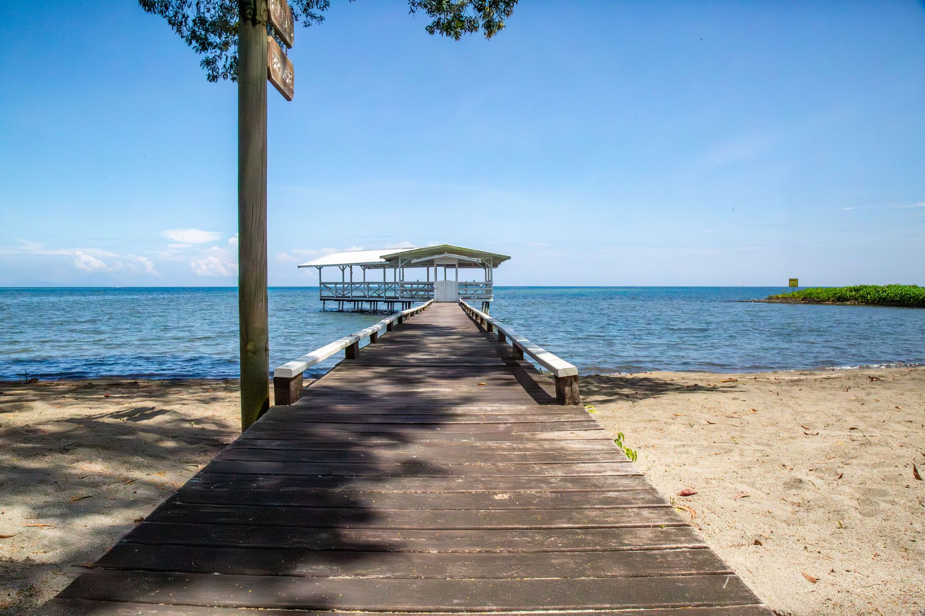Wooden pier leading to a serene ocean view under a clear sky, ideal summer day.