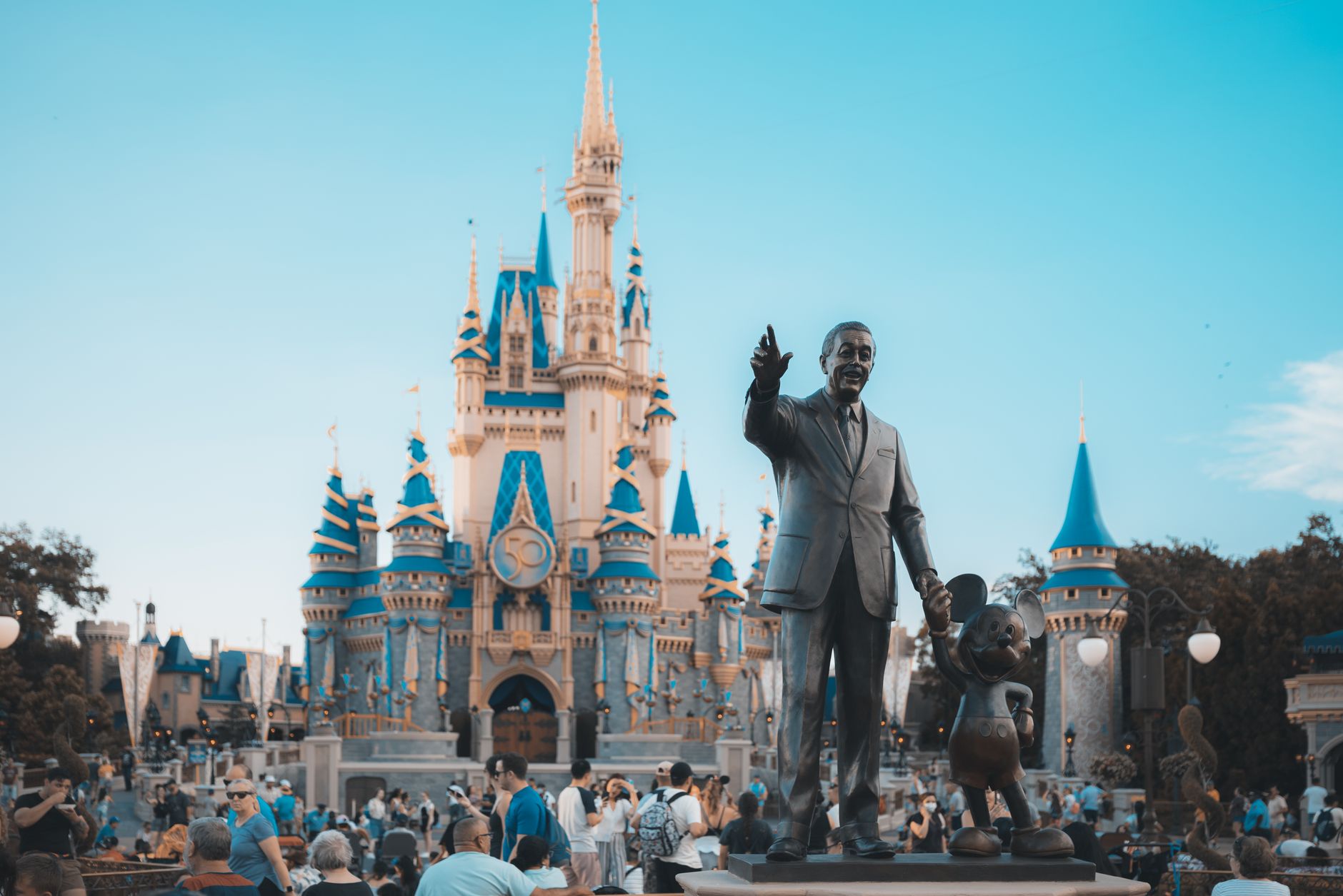View of the iconic Cinderella Castle at Walt Disney World in Orlando, Florida, with crowd and statue.
