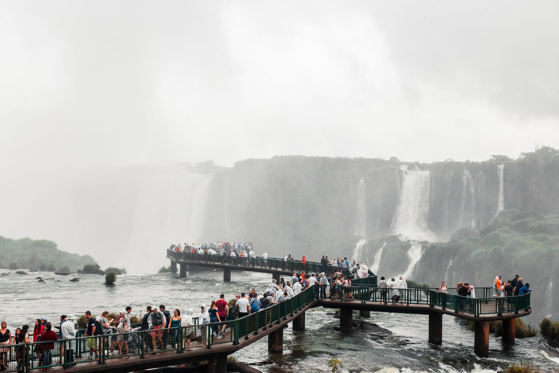 Visitors explore the breathtaking Iguazu Falls on a misty day in Brazil.