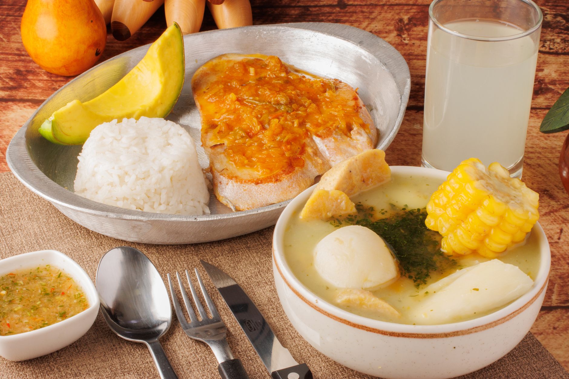 Delight in a traditional Colombian meal featuring ajiaco soup, rice, avocado, and tamarind juice.