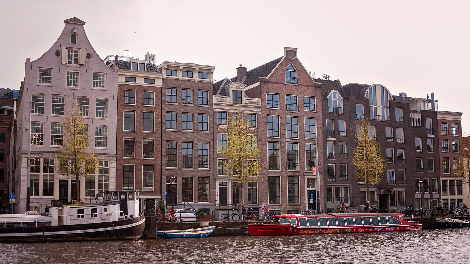 Charming canal-side view of traditional Amsterdam houses and passenger boats.