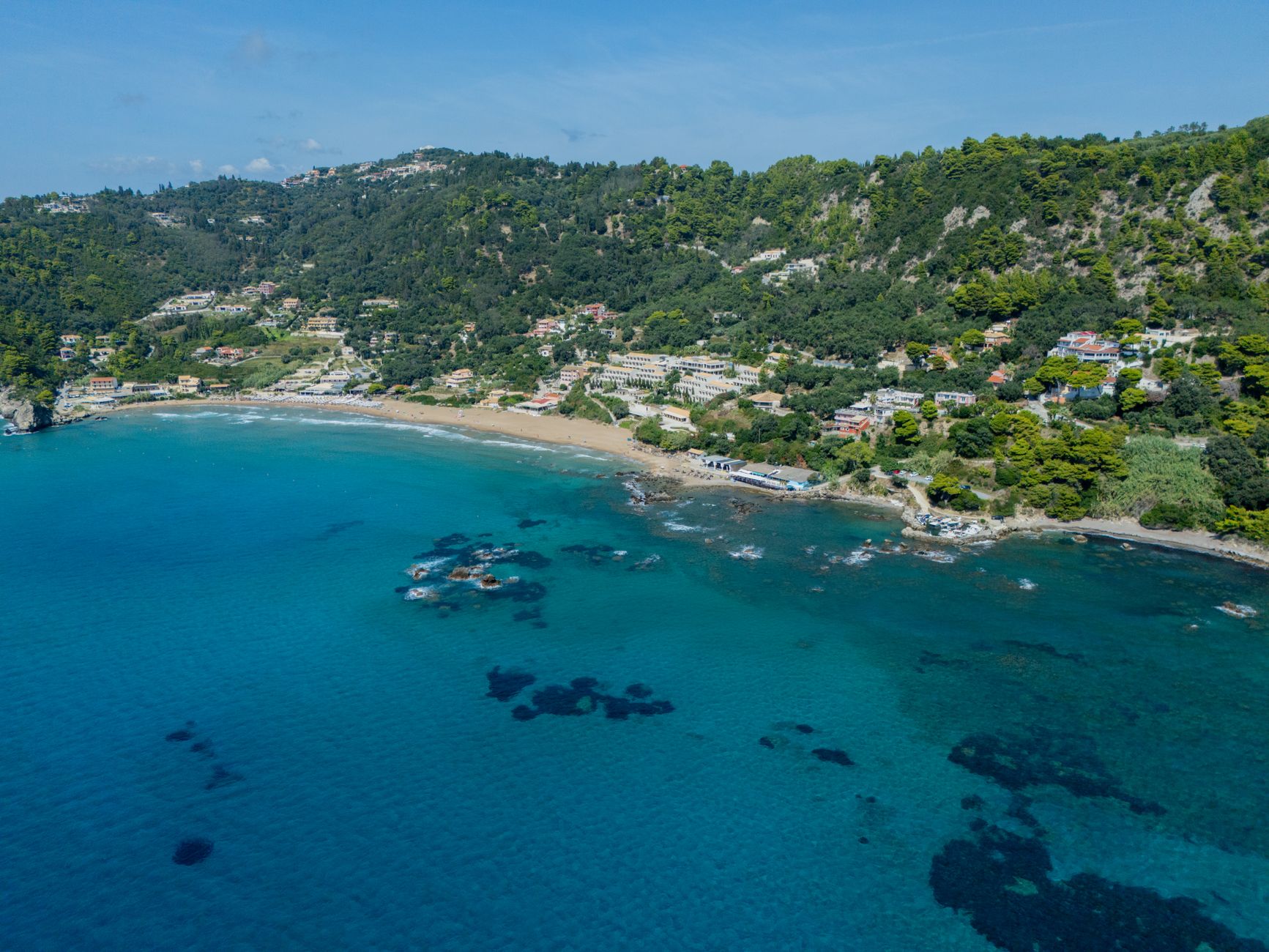 Stunning aerial view of Glyfada Beach on Corfu Island, Greece, with clear azure waters and lush greenery.