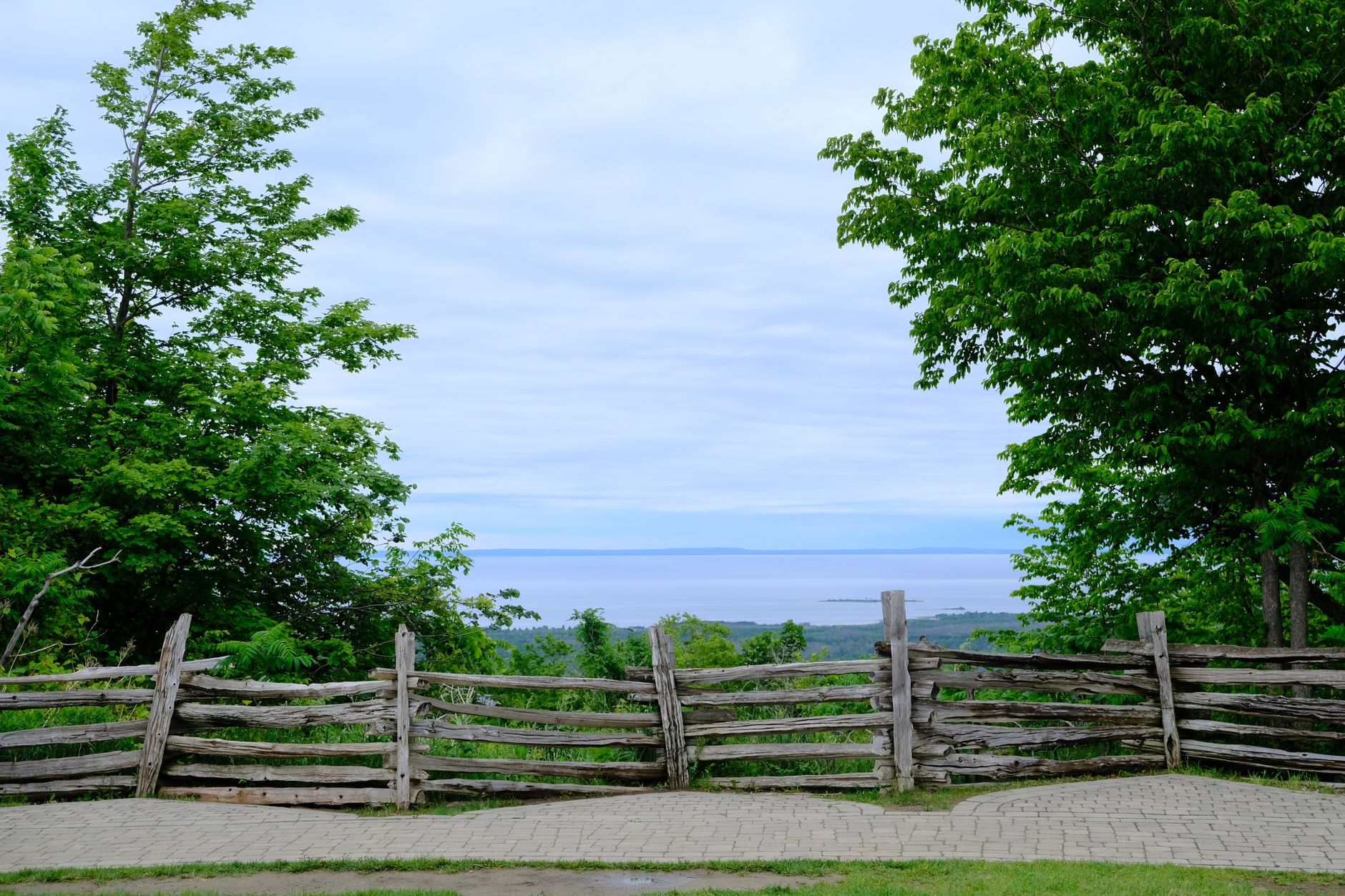 Tranquil landscape of the Blue Mountains, Ontario, featuring a rustic fence and lush greenery.