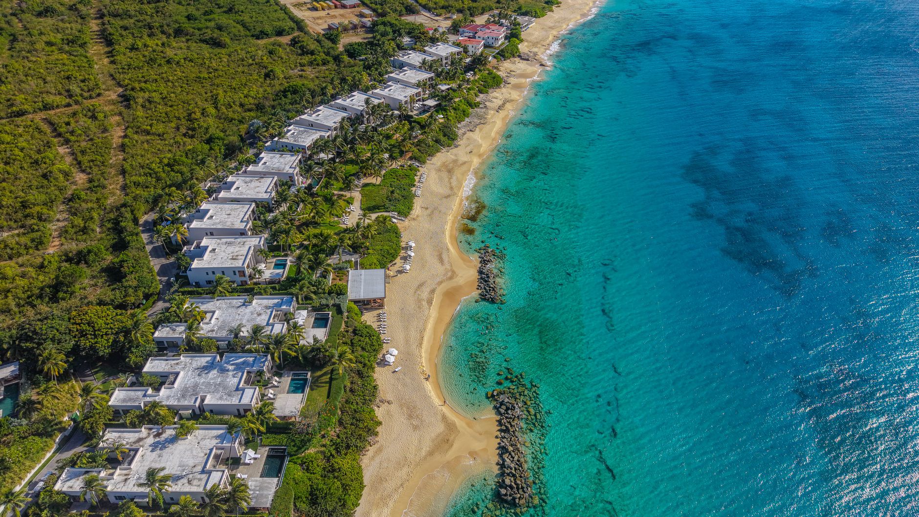 A stunning aerial image of luxury resorts along the coastline of Anguilla with turquoise waters.