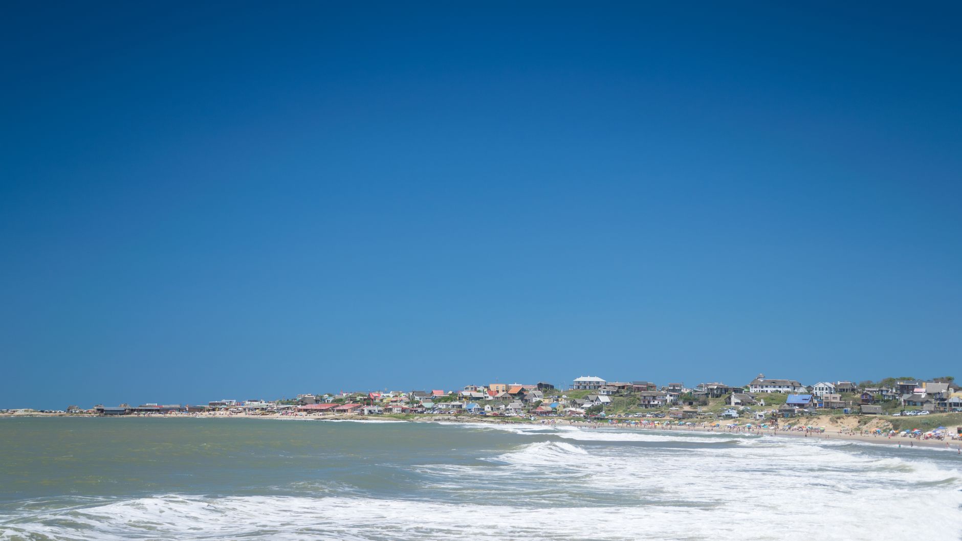 A picturesque coastal view of Punta del Diablo, Uruguay with vibrant blue skies and waves.