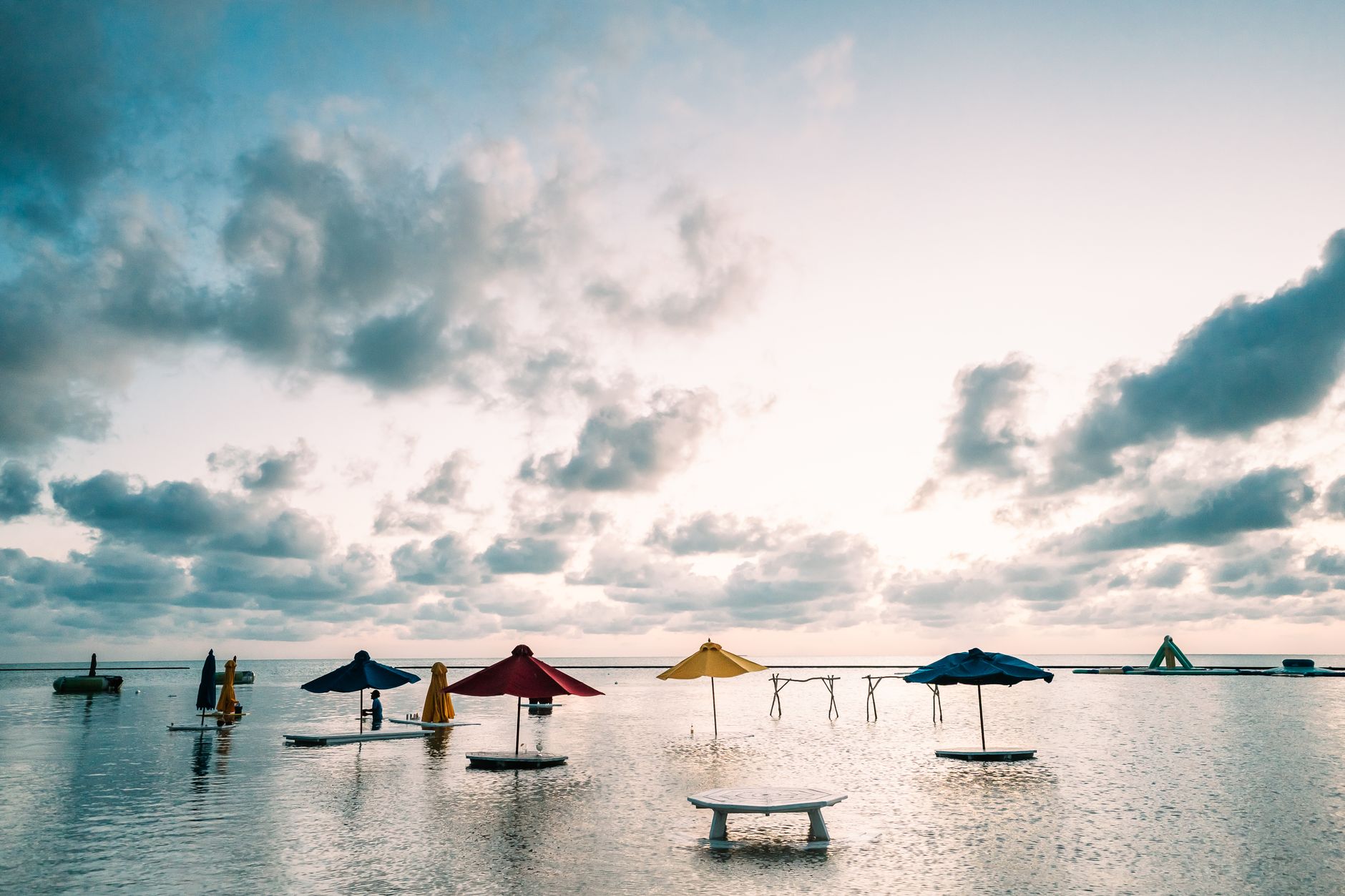 Peaceful beach setting with colorful parasols over calm waters in San Pedro, Belize at sunrise.