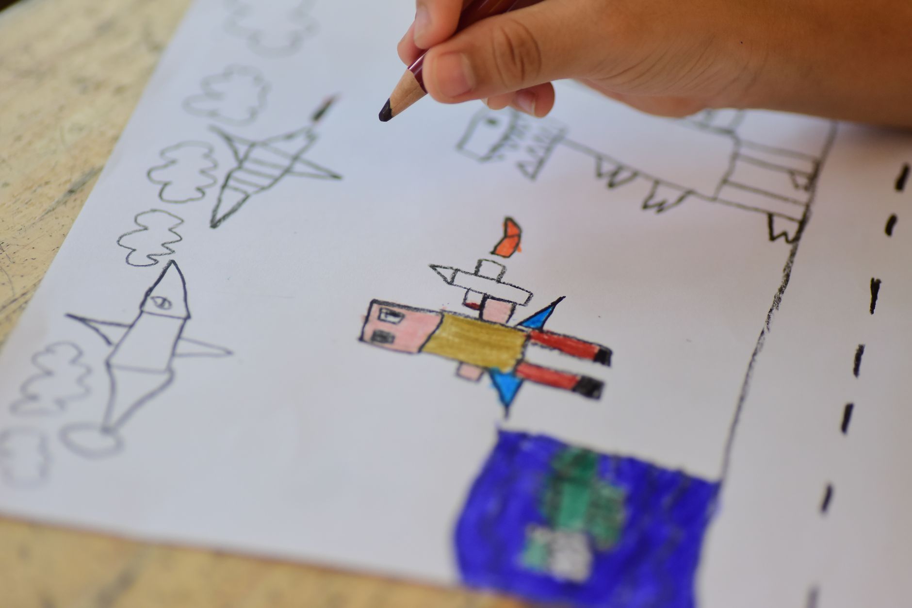 Close-up of a child drawing spaceships and astronauts. Creative art expression in a playful setting.