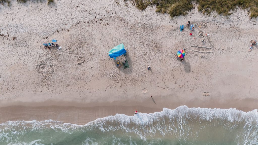 Aerial shot of Fort Pierce beach depicting sand, sea, and beachgoers enjoying a sunny day.