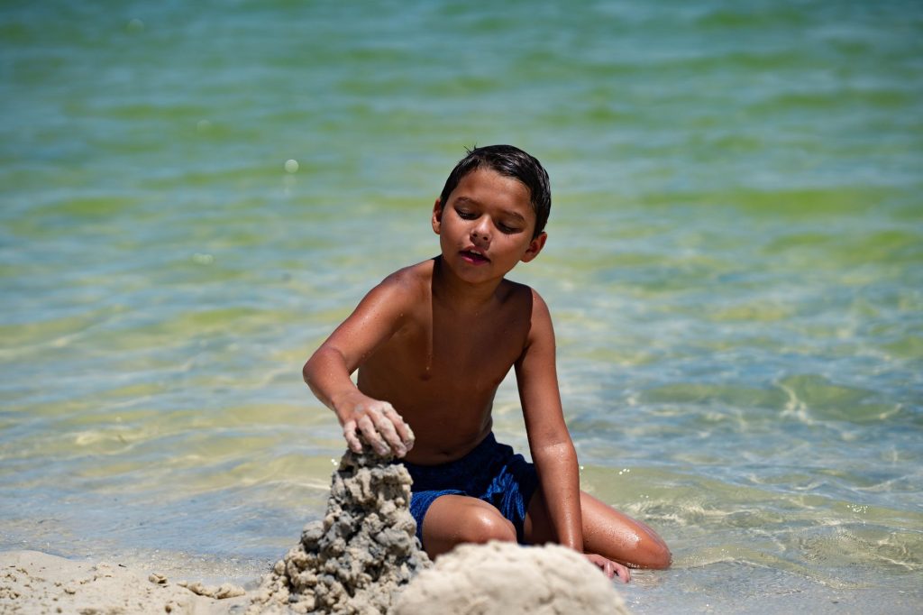 Young boy enjoying a sunny day building a sandcastle on a beach in Hudson, Florida.